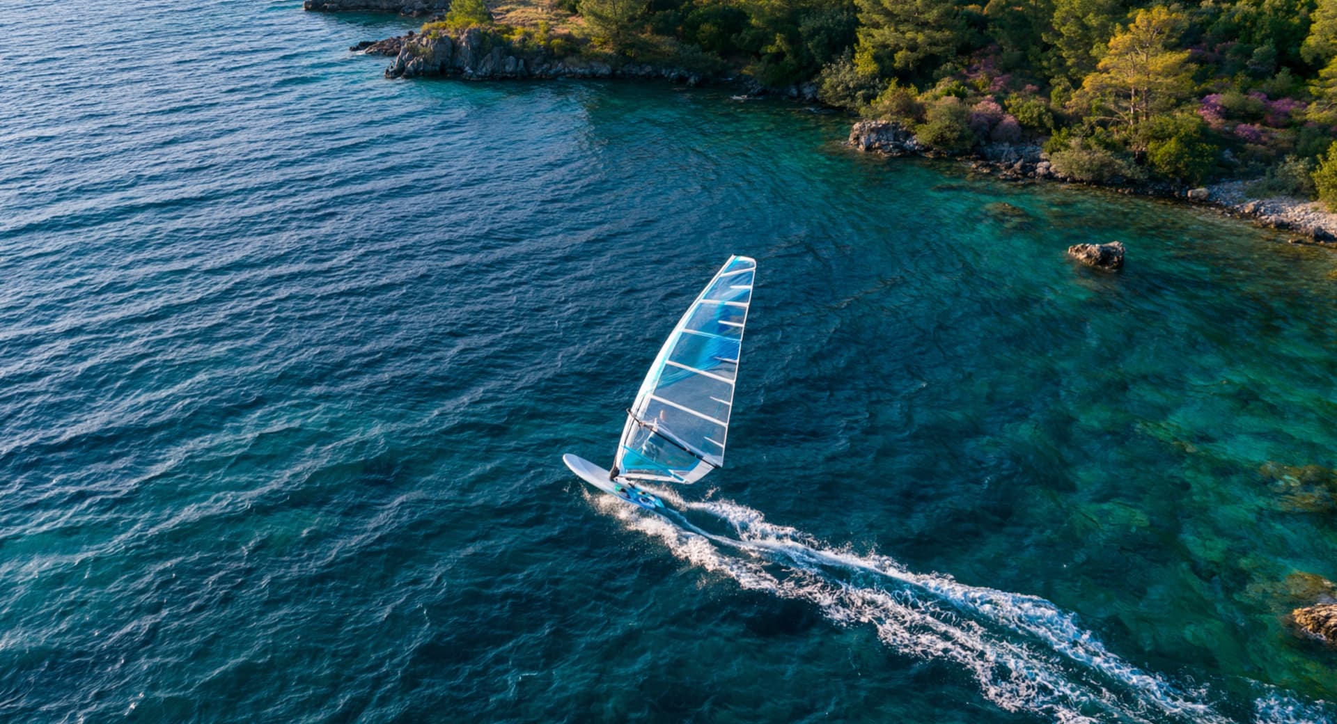 Aerial view of windsurfer gliding through turquoise waters